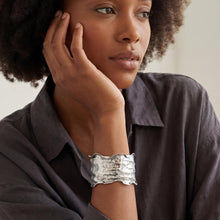 Load image into Gallery viewer, A woman with curly hair wearing a gray shirt and a silver cuff bracelet is looking off to the side.