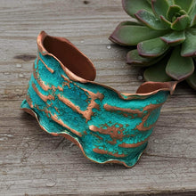 Load image into Gallery viewer, A turquoise-colored cuff bracelet with a textured, wavy design sits on a wooden surface next to a green succulent plant.