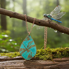 Load image into Gallery viewer, May include: A copper-colored necklace with a teal teardrop pendant featuring a dragonfly design. The pendant hangs from a delicate chain. A decorative dragonfly rests on a branch, with a mossy log in the foreground.