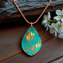 Load image into Gallery viewer, A turquoise patina teardrop pendant with etched copper tulip designs hanging from a copper snake chain