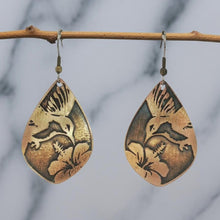 Load image into Gallery viewer, A pair of earrings with a bird and flower design, hanging from a wooden branch.