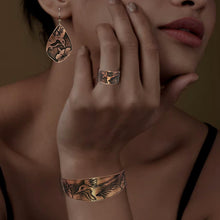 Load image into Gallery viewer, A close-up of a woman's hand wearing a ring and bracelet, with a pensive expression on her face.