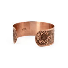 Load image into Gallery viewer, a copper bracelet with a floral design on it.

