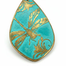 Load image into Gallery viewer, A close-up image of a decorative pendant or earring with a teal blue background and gold leaf-like patterns.

