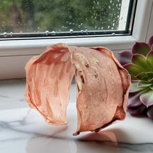 Load image into Gallery viewer, a copper-colored, textured bracelet with a unique, organic shape, placed on a marble surface next to a potted succulent plant.
