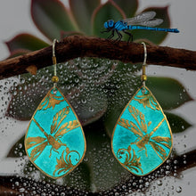 Load image into Gallery viewer, A pair of turquoise earrings with gold leaf designs, hanging from a branch with a blue dragonfly perched on it.
